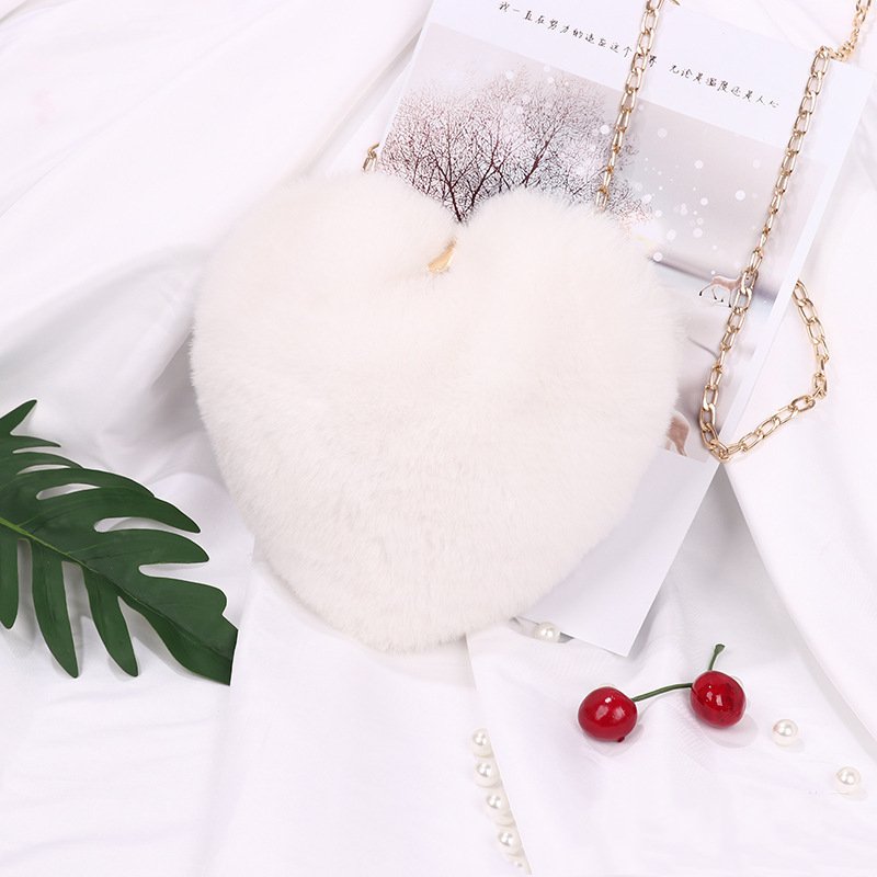 Plush heart-shaped shoulder bag with chain strap and zipper, shown in one of the available colors.